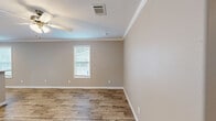 Located at 9101 Normandy Boulevard in Jacksonville, FL, this single-story, 3-bedroom, 2-bathroom home offers a clean, modern aesthetic throughout. The interior is unified by warm wood-look luxury vinyl plank flooring and neutral taupe-toned walls, complemented by crisp white crown molding and baseboards that add a polished finish to every room.

The heart of the home is an open-concept living, dining, and kitchen area. The kitchen is well-equipped with white shaker-style cabinetry, white countertops, stainless steel appliances including a side-by-side refrigerator, dishwasher, and range, plus a pantry for additional storage. Recessed lighting and a window above the sink keep the space bright and functional. A breakfast bar provides a natural transition into the dining and living areas, which feature ceiling fans and windows dressed with white blinds.

The three bedrooms are comfortably sized, each with crown molding, ceiling fans or light fixtures, and natural light from windows. The primary bedroom includes an en-suite bathroom with a vanity, sliding glass shower enclosure, and wood-look flooring. The second bathroom features a full tub-shower combination with clean white surround. Additional highlights include four closets, a dedicated laundry area, a hallway, and a welcoming entrance, making this home highly functional and move-in ready.