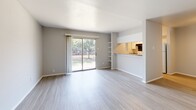 Located at 3800 Portland St in Irving, TX, this one-bedroom, one-bathroom unit offers a well-organized single-floor layout designed for comfortable, efficient living. The open-concept living room is bright and airy, featuring light wood-style flooring and a sliding glass door that leads to a private patio, flooding the space with natural light and offering pleasant outdoor views of surrounding greenery. A built-in shelving unit flanks the pass-through opening to the kitchen, adding both character and functionality to the living area. The galley-style kitchen is thoughtfully arranged with white cabinetry, gray laminate countertops, a double sink, dishwasher, and full-size refrigerator, along with a window that brings in additional natural light. The spacious bedroom features soft carpeting, a ceiling fan with light fixture, a window with blinds, and direct access to a dedicated closet, providing ample storage. The full bathroom includes a tub-shower combination with tiled surround, a toilet, and a vanity with countertop, all finished with light wood-style flooring. The unit's neutral color palette throughout creates a clean, cohesive aesthetic that is both practical and inviting.