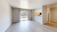 Located at 3800 Portland St in Irving, TX, this one-bedroom, one-bathroom unit offers a well-organized single-floor layout designed for comfortable, efficient living. The open-concept living room is bright and airy, featuring light wood-style flooring and a sliding glass door that leads to a private patio, flooding the space with natural light and offering pleasant outdoor views of surrounding greenery. A built-in shelving unit flanks the pass-through opening to the kitchen, adding both character and functionality to the living area. The galley-style kitchen is thoughtfully arranged with white cabinetry, gray laminate countertops, a double sink, dishwasher, and full-size refrigerator, along with a window that brings in additional natural light. The spacious bedroom features soft carpeting, a ceiling fan with light fixture, a window with blinds, and direct access to a dedicated closet, providing ample storage. The full bathroom includes a tub-shower combination with tiled surround, a toilet, and a vanity with countertop, all finished with light wood-style flooring. The unit's neutral color palette throughout creates a clean, cohesive aesthetic that is both practical and inviting.