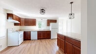 Located at 1335A Mertensia Rd in Farmington, NY, this three-bedroom, two-bathroom home is thoughtfully laid out across three floors, offering generous living space with a practical and functional design. The main level features a combined kitchen and dining area highlighted by rich cherry-toned cabinetry, granite-look countertops, light hardwood-style flooring, and a full suite of white appliances. Natural light filters in through multiple windows, with pendant and flush-mount lighting adding a warm ambiance. The entry features a charming arched window door flanked by a spacious closet. The living room is bright and open, with clean neutral walls and consistent hardwood-style flooring throughout. Each of the three bedrooms is well-proportioned, offering closet storage and natural light from tree-lined views outside. The primary bedroom provides a comfortable, private retreat. Both bathrooms are clean and simply appointed, one featuring a tub-shower combination with a window above. The unfinished basement presents a wide-open footprint with concrete floors and utility access, ideal for storage or future customization. A balcony adds outdoor access, completing this versatile multi-floor home.