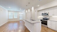 This thoughtfully designed 2-bedroom, 2-bathroom single-story residence offers a clean, modern aesthetic with an efficient and functional layout. The open-concept living and kitchen area serves as the heart of the home, anchored by a central island finished with granite countertops and an undermount sink, illuminated by sleek pendant lighting. The kitchen is equipped with stainless steel appliances, white shaker-style cabinetry extending to the ceiling, and a bright, cohesive finish. A built-in desk nook adds a practical workspace within the living area.

Warm hardwood-style flooring flows consistently throughout the entire residence, complemented by crisp white walls, crown molding, and recessed lighting. Natural light filters in through multiple windows fitted with blinds, creating a bright and welcoming ambiance.

The primary bedroom is a comfortable and well-proportioned retreat, connected to an en-suite bathroom featuring a granite-topped vanity and access to a walk-in closet with built-in shelving and hanging rods. The second bathroom mirrors the same refined finishes, offering a full tub-shower combination with white subway tile surround and a matching granite vanity. A hallway and two closets provide additional storage, completing this well-organized and move-in-ready residence.
