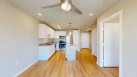 This efficiently designed 1-bedroom, 1-bathroom residence offers a thoughtful layout across a single floor, making excellent use of every square foot. Light hardwood flooring flows consistently throughout the unit, lending a clean and cohesive aesthetic.

The kitchen serves as a standout feature, equipped with crisp white shaker cabinetry, granite countertops, and a full suite of stainless steel appliances including a refrigerator, range, microwave, and dishwasher. A central island with matching granite provides additional prep space and casual seating potential, while pendant lighting adds a contemporary touch overhead.

The open living area connects seamlessly to the kitchen, benefiting from recessed lighting and a ceiling fan. A sliding glass door leads to a private balcony, allowing for natural light and outdoor views.

The bedroom is a well-proportioned retreat, featuring a ceiling fan with a large window framing exterior views. It is complemented by a dedicated walk-in closet with built-in shelving for ample storage.

The bathroom is finished with white cabinetry, granite countertops, an overhead vanity light, and additional upper cabinet storage. Neutral warm-toned walls throughout the unit contribute to a bright, welcoming atmosphere.