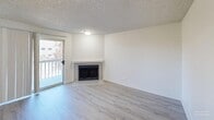 Located in Tacoma, WA, this one-bedroom unit offers a practical and well-appointed single-floor layout. The combined living and dining area serves as the heart of the home, featuring light-toned laminate flooring, crisp white walls, and a textured ceiling. A corner fireplace with a tile surround adds a focal point to the living room, while a sliding glass door opens to a private balcony, allowing natural light to fill the space and providing outdoor views.

The galley-style kitchen is efficiently designed with white shaker cabinetry, light quartz countertops, and black stainless appliances including a range, built-in microwave, and refrigerator. A window over the adjoining dining nook brings in additional natural light.

The bedroom is a comfortable retreat, finished with plush wall-to-wall carpeting and a large window that frames views of surrounding greenery. The textured ceiling carries throughout, giving the unit a consistent aesthetic.

Additional areas include a separate room with laminate flooring that functions well as a dining space or home office. The unit's clean, neutral palette and updated finishes provide a move-in-ready environment well-suited for everyday living in a convenient Tacoma location.