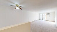 This single-floor residence offers a clean, functional layout designed for comfortable everyday living. The main living area is generously sized, featuring soft wall-to-wall carpeting, neutral white walls, and a ceiling fan with integrated lighting that promotes year-round comfort. A sliding glass door leads to a private balcony, allowing natural light to fill the room and providing views of the surrounding outdoor environment. Baseboard heating runs along the perimeter, ensuring efficient warmth throughout the space.

The bedroom is well-proportioned with carpeted flooring, a large window that invites natural light and outdoor views, and a sliding closet with ample storage space. The warm wood tones of the closet doors and interior trim add a consistent design element across the space.

A utility area features durable wood-look flooring and houses the electrical panel, keeping essential systems accessible and organized. The overall color palette is light and neutral throughout, with white walls and warm wood accents contributing to a bright, airy atmosphere. The layout flows cohesively from one area to the next, making the space feel open and easy to navigate. This residence combines practicality with a welcoming ambiance suitable for a variety of living arrangements.