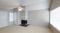 This single-story space is designed with a neutral, light-filled palette throughout, creating a calm and cohesive atmosphere. The living area serves as a central gathering point, anchored by a tile-surround fireplace with a white mantel and accented by a vaulted ceiling section that adds visual depth. A ceiling fan overhead and plush carpeting underfoot contribute to the room's comfortable feel.

The kitchen features white cabinetry, granite-style countertops, and white appliances, including a refrigerator, range, and built-in microwave. A peninsula counter separates the kitchen from the adjoining carpeted dining or living area, which benefits from natural light streaming through a window. A half bath is conveniently accessible directly from this space.

The bedroom is generously proportioned, featuring soft carpet, a ceiling fan, a large window for natural light, and full-length mirrored sliding closet doors that enhance the sense of space. A glass-paned French door adds a refined architectural detail.

The full bathroom is finished with wood-look flooring, white cabinetry, granite-style countertops, a large vanity mirror, and a tub-shower combination, offering both function and clean, updated style.
