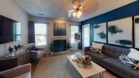 Located at 455 Arbor Pl in Nashville, TN, this single-story residence offers a well-organized floor plan with a cohesive, contemporary design anchored by striking deep teal accent walls throughout. The living room serves as the heart of the home, featuring a tiled fireplace flanked by multiple windows that invite natural light, a ceiling fan with light fixture, wood-look flooring, and a textured ceiling. Bold abstract artwork and a richly layered furniture arrangement give the space a curated, stylish character. Adjacent to the living area, a dedicated dining space continues the teal accent theme, highlighted by a pendant light overhead and hardwood-style flooring. The galley-style kitchen is thoughtfully laid out with white cabinetry, mosaic tile backsplash, black appliances including a range and refrigerator, a double basin sink, and ample counter space. The bedroom offers a comfortable retreat with plush carpet, warm ambient lighting, and a sliding glass door that opens to a private balcony with outdoor views of surrounding greenery. The bathroom features a full tub-shower combination, a wide vanity with a framed mirror, white cabinetry, and soft overhead lighting, providing a clean and functional finish to the space.