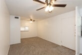 Located at 4314 16th St in Lubbock, Texas, this single-story residence offers a straightforward and functional layout designed for comfortable everyday living. The main living area is generously sized, featuring warm beige carpeting, crisp white walls, and a textured ceiling with a ceiling fan and light fixture that provides both comfort and illumination. A pass-through window connects the living area to the kitchen, enhancing the open feel between spaces. Tile flooring marks the entryway and transitions seamlessly into the carpeted living zones. The kitchen is equipped with a range and countertop workspace, with white cabinetry providing ample storage. The bedrooms continue the neutral color palette, each with plush carpet flooring, ceiling fans with light kits, and windows that allow natural light to filter in, offering views of the surrounding greenery. Six-panel interior doors with brass hardware add a classic touch throughout. The bathroom features full tile surround in warm earth tones framing a soaking tub and shower combination, complemented by tile flooring and built-in cabinetry. The space as a whole presents a clean, move-in ready environment with consistent finishes and practical amenities throughout.