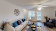 This thoughtfully designed single-floor residence offers a comfortable and functional layout across several well-defined living spaces. The living room serves as the heart of the home, featuring warm wood-style flooring, a ceiling fan with light fixture, and large windows alongside a glass-paneled door that floods the space with natural light and provides access to an outdoor patio area. The open, welcoming atmosphere is complemented by neutral wall tones throughout.

The galley-style kitchen is efficiently laid out with ample cabinetry, white appliances including a stove, microwave, dishwasher, and refrigerator, along with a double-basin sink and generous counter space. A dedicated laundry area with washer and dryer hookups is conveniently accessible directly from the kitchen.

The dining area is a defined space highlighted by a pendant light fixture, ideal for everyday meals or entertaining. The primary bedroom is generously sized with plush carpeting, a ceiling fan, natural light from a window with draping curtains, and ample room for large furniture. A second bedroom offers similar finishes, a walk-in closet, and flexible space suitable as a home office or guest room.

Two full bathrooms serve the residence — one featuring a vanity with a large mirror, wood-style flooring, and a shower-tub combination, while the second offers a clean, neutral design with a shower and additional storage. Together, the rooms create a cohesive, move-in-ready living environment.