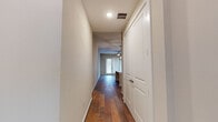 This single-story home offers a thoughtfully designed layout that balances comfort and modern style. Rich hardwood flooring flows throughout the main living areas, beginning at the entry hallway that leads guests toward the open living and kitchen spaces. The kitchen serves as a centerpiece of the home, showcasing gray shaker-style cabinetry, crisp white quartz countertops, and a full suite of stainless steel appliances including a refrigerator, range, and over-the-range microwave. A large center island with an undermount sink and striking geometric pendant lights above adds both function and visual appeal. The adjacent living area is open and airy, providing a generous canvas for personalization. A versatile bonus room features French doors fitted with blinds, a ceiling fan, and gleaming hardwood floors, offering flexible use as a dining room, office, or sitting area. The bedrooms are carpeted for comfort, each equipped with ceiling fans and windows dressed with blinds that welcome natural light. The bathroom is finished with large-format tile, a full tub-shower combo with tiled surround, and a vanity with matching gray cabinetry. Throughout the home, neutral tones and clean lines create a cohesive, move-in-ready aesthetic.