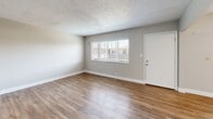 Located at 557-559 Buena Vista Ave in Alameda, CA, this one-bedroom, one-bathroom unit offers a practical and well-maintained single-floor layout. The living room is a welcoming space featuring wood-look laminate flooring, neutral beige walls, a textured ceiling, and a large window fitted with plantation-style blinds that allow for ample natural light. A ceiling fan provides additional comfort in the bedroom, which also benefits from a wide window and a sliding-door closet, all set over plush carpeting that adds warmth underfoot. The kitchen is efficiently designed with white cabinetry, light countertops, and stainless steel appliances including a refrigerator and electric range, complemented by wood-look flooring that ties the space together. The bathroom is clean and functional, offering a combined tub and shower with tile surround, a white vanity with under-cabinet storage, and a window that brings in natural light. A connecting hallway links the rooms seamlessly. Throughout, the unit maintains a consistent, neutral color palette with white trim and baseboards, creating a clean and cohesive aesthetic well-suited to everyday living.
