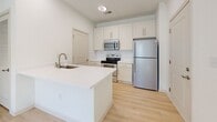 Located at 11920 Joleen Ct in Huntersville, NC, this single-floor, one-bedroom, one-bathroom unit offers a well-designed layout that maximizes every square foot. The interior is finished in a bright, neutral palette of whites and soft tones, creating a clean and cohesive aesthetic throughout.

The kitchen serves as a central highlight of the space, featuring white shaker-style cabinetry, white quartz countertops, and a peninsula island with an undermount sink. Stainless steel appliances — including a refrigerator, electric range, over-the-range microwave, and dishwasher — are neatly integrated into the layout. Light wood-look flooring runs throughout the main living and kitchen areas, contributing to a warm, airy feel.

The bedroom offers a comfortable footprint with soft carpeting, crisp white walls, and double doors leading to a closet, providing practical storage. The room is well-proportioned for a cozy yet functional retreat.

The bathroom is finished with light wood-look flooring and includes a full tub-shower combination with white tile surround, a toilet, and a vanity with a light countertop. Brushed nickel fixtures and a towel bar add consistent, understated detail.

Overall, the unit presents a tidy, move-in-ready space with modern finishes and functional design suited for efficient single-occupant living.
