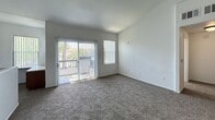Located at 5880 Boulder Falls St in Henderson, NV, this 2-floor residence offers 810 square feet of functional living space. The ground floor (90 sq ft) houses an attached single-car garage with an automatic opener and concrete flooring, providing convenient interior access via a staircase leading to the main living level. The upper floor (720 sq ft) encompasses all living areas, finished with consistent carpet throughout the bedrooms and living spaces, and durable wood-style flooring in the kitchen. The open-concept kitchen and living room combination features rich, dark wood cabinetry, granite-style countertops, a gas range, built-in microwave, refrigerator, double basin sink, and track lighting overhead. The living area is bright and airy, boasting vaulted ceilings, a ceiling fan, and large sliding glass doors with vertical blinds that open to an outdoor balcony with neighborhood views. The primary bedroom (150 sq ft) includes a sliding glass door with outdoor access, an additional window for ample natural light, and connects to a dedicated walk-in closet equipped with wire shelving and hanging rods. The home's clean, neutral palette throughout creates a bright, move-in ready environment.