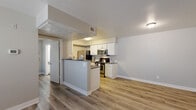 Located at 3985 E Cheyenne Ave in Las Vegas, Nevada, Unit 236 is a single-floor residence that combines functional design with clean, contemporary finishes. Light wood-grain luxury vinyl plank flooring runs throughout the unit, providing a cohesive and low-maintenance foundation across all living areas.

The kitchen is a standout feature, designed with white cabinetry offering ample storage, dark countertops, and a full suite of stainless steel appliances including a range, microwave, and refrigerator. A peninsula with counter seating opens the kitchen toward the adjacent living area, promoting an open and connected layout ideal for both everyday living and entertaining.

The living area is generously proportioned, with neutral gray walls, white panel doors, and a textured ceiling. A large window fitted with horizontal blinds invites natural light into the bedroom area, which also includes a wall-mounted thermostat for individual climate control.

The bathroom is well-appointed with a single-sink vanity featuring a dark countertop, a full-size mirror, and a tub-shower combination with white tile surround. Throughout the unit, white baseboards and neutral tones create a clean, move-in ready aesthetic that suits a variety of décor styles. The overall design prioritizes practicality and comfort in a compact, efficiently organized single-level layout.
