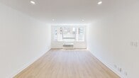 807 Studio is a thoughtfully designed studio that maximizes its single-floor layout with a clean, modern aesthetic throughout. The combined kitchen and living area forms the heart of the space, bathed in natural light from a large picture window that frames urban cityscape views. Light wood flooring runs throughout, complemented by crisp white walls and recessed ceiling lighting that enhances the bright, airy atmosphere. A wall-mounted HVAC unit ensures year-round comfort beneath the window.

The kitchen is efficiently arranged in an L-shaped configuration, featuring light wood cabinetry with matte black hardware, a quartz countertop with subtle veining, and a full suite of stainless steel appliances including a refrigerator, electric range, built-in microwave, and dishwasher. A undermount sink with a modern faucet completes the functional workspace.

The bathroom showcases a refined design with a frameless glass-enclosed shower finished in floor-to-ceiling marble-look tile and accented with matte black fixtures, including a rainfall showerhead and towel bar. A built-in shower niche adds convenience, while a double-door closet provides additional storage. The overall design of 807 Studio combines practical functionality with contemporary finishes for a polished, move-in-ready living space.
