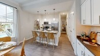 Located at 134 Village Club Dr in Mooresville, NC, this well-appointed one-bedroom, two-bathroom residence offers a thoughtfully designed single-floor layout. The open-concept living, dining, and kitchen area serves as the heart of the home, bathed in natural light from large windows overlooking a lush outdoor setting with pool views. Crown molding adds a refined touch throughout the main living spaces.

The kitchen features crisp white cabinetry, dark quartz countertops, stainless steel appliances including a French-door refrigerator, a double-basin sink, and stylish pendant lighting that flows naturally into the dining area. The dining space is anchored by a classic chandelier and a generous window framing serene outdoor views.

The living room is bright and welcoming, with oversized windows, hardwood-style flooring, and direct access to an outdoor balcony. The primary bedroom offers plush carpeting, a ceiling fan, ample natural light, and a tranquil outdoor view. Both bathrooms are finished with white cabinetry and dark stone countertops. A dedicated laundry room with a full-size washer and dryer adds everyday convenience. A hallway adorned with a charming porthole mirror connects the spaces with a subtle nautical accent.