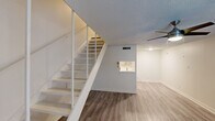 This two-story, one-bedroom, one-bathroom residence in Austin, TX is thoughtfully distributed across two levels, offering a functional and well-organized layout. The main floor houses the primary living areas, where wood-style laminate flooring runs throughout, complemented by neutral white walls and a textured ceiling. A white open-riser staircase connects both levels and serves as a visual focal point of the main living space, while a ceiling fan provides additional comfort overhead.

The galley-style kitchen is accessible from the main living area and features gray shaker cabinetry with brushed nickel hardware, white quartz countertops, a stainless steel sink, and stainless steel appliances including an electric range and refrigerator. Light wood-style flooring continues into the kitchen, maintaining a cohesive aesthetic throughout.

Upstairs, the spacious primary bedroom offers ample storage through multiple built-in closets with shelving, wood-style flooring, and a ceiling fan with light fixture. A window brings in natural light, creating a comfortable retreat.

The full bathroom includes a tub-shower combination with white tile surround, a single-sink vanity with a white countertop, and a mirror, providing a clean and functional space. Overall, the residence offers an efficient, modern feel suited for Austin living.