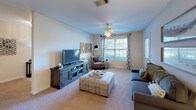 This single-floor residence offers a thoughtfully designed layout that balances comfort and functionality throughout. The living room serves as the heart of the home, featuring plush carpeting, a ceiling fan, and a large window that fills the space with natural light and outdoor views. The room flows naturally toward additional living areas, creating an open and connected feel.

The dining area is a welcoming space anchored by a round table beneath a statement pendant light, complemented by a warm wood sideboard and framed wall art, making it ideal for everyday meals and entertaining alike.

The kitchen is well-equipped with white cabinetry, ample counter space, and full appliances including a range, dishwasher, and refrigerator. Stone-patterned tile flooring adds a practical and stylish touch.

The primary bedroom offers a ceiling fan, carpeted floors, natural light through a window, and direct access to a walk-in closet and en-suite bathroom. The en-suite features a double vanity and tile flooring. A second full bathroom includes a tub-shower combination and matching tile flooring.

Additional bedrooms are generously sized with carpeted floors, closets, and windows providing natural light — well-suited for use as children's rooms, guest spaces, or a home office. The overall ambiance is bright, neutral, and move-in ready.