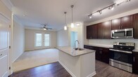 This single-floor residence offers a thoughtfully designed open-concept layout that seamlessly connects the kitchen and living areas. The kitchen is a standout feature, showcasing rich dark-wood cabinetry, granite countertops, and a central island with an undermount sink and elegant pendant lighting overhead. Stainless steel appliances, including a refrigerator and microwave, complement the space, while wood-style flooring adds warmth and durability underfoot. Track lighting provides additional illumination throughout the kitchen.

The living area transitions naturally from the kitchen, featuring plush carpeting, crown molding, and a ceiling fan. French doors lead to an outdoor balcony, allowing natural light to fill the room and offering views of the surrounding neighborhood.

The bedrooms are generously sized, each with soft carpeting, ceiling fans, and windows that bring in ample natural light. The bathrooms are finished with granite-topped dark-wood vanities, wood-style flooring, and tub-shower combinations. A walk-in closet is accessible from one of the bathrooms, providing convenient and well-organized storage. Overall, the space combines functional design with tasteful finishes to create a comfortable and cohesive living environment.
