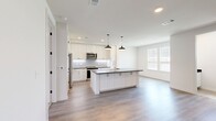 This well-designed three-story home offers a thoughtful layout across three distinct levels, combining modern aesthetics with practical functionality. The ground floor provides direct garage access, while the main living level serves as the heart of the home. The kitchen is a standout feature, showcasing white shaker-style cabinetry, a subway tile backsplash, stainless steel appliances, and a large center island with a dark countertop and pendant lighting — seamlessly opening to the living area with light hardwood flooring and ample natural light from large windows. Staircases with wood-tread steps connect all three floors with clean, contemporary railings and crisp white walls. The upper floor hosts the three bedrooms, each with plush carpeting and ceiling fans. The primary bedroom includes a dedicated closet and private bathroom access. The four bathrooms are finished with large-format tile, dark countertops, white cabinetry, and frameless glass shower enclosures alongside soaking tubs. Three closets provide generous storage throughout, and a dedicated laundry area comes equipped with a full-size washer and dryer. The home's consistent palette of white walls, warm wood flooring, and dark accents creates a cohesive, modern ambiance.