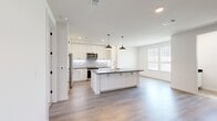 This well-designed three-story home offers a thoughtful layout across three distinct levels, combining modern aesthetics with practical functionality. The ground floor provides direct garage access, while the main living level serves as the heart of the home. The kitchen is a standout feature, showcasing white shaker-style cabinetry, a subway tile backsplash, stainless steel appliances, and a large center island with a dark countertop and pendant lighting — seamlessly opening to the living area with light hardwood flooring and ample natural light from large windows. Staircases with wood-tread steps connect all three floors with clean, contemporary railings and crisp white walls. The upper floor hosts the three bedrooms, each with plush carpeting and ceiling fans. The primary bedroom includes a dedicated closet and private bathroom access. The four bathrooms are finished with large-format tile, dark countertops, white cabinetry, and frameless glass shower enclosures alongside soaking tubs. Three closets provide generous storage throughout, and a dedicated laundry area comes equipped with a full-size washer and dryer. The home's consistent palette of white walls, warm wood flooring, and dark accents creates a cohesive, modern ambiance.