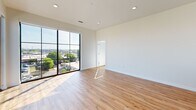This thoughtfully designed three-bedroom, two-bathroom residence in Richmond, Virginia offers a bright and modern living experience across a single floor. The open living area is anchored by dramatic floor-to-ceiling grid windows that flood the space with natural light and frame sweeping views of the surrounding Richmond cityscape. Warm hardwood-style flooring runs throughout, lending a cohesive and contemporary feel to the entire home.

The kitchen is well-appointed with white shaker cabinetry, quartz countertops, a subway tile backsplash, and a full suite of stainless steel appliances, including a range, over-the-range microwave, refrigerator, and dishwasher. A large window in the kitchen provides additional natural light and city views.

The primary bedroom is generously sized, featuring large windows and a walk-in closet with wire shelving systems for organized storage. The two additional bedrooms are comfortable and bright, each with ceiling fans and their own closet access. A second walk-in closet adds further storage flexibility.

The two bathrooms are finished in a clean, modern palette with tile flooring. One features a tub-shower combination with a curved rod, while the other offers a glass-enclosed walk-in shower, a single-sink vanity with wood-toned cabinetry, and a built-in niche. A connecting hallway ties all rooms together efficiently.
