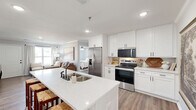 Located at 101 Eastline Rd in Searcy, Arkansas, this single-story 2-bedroom, 2-bathroom home offers a thoughtfully designed layout with modern finishes throughout. The open-concept kitchen and dining area serves as the heart of the home, showcasing crisp white shaker cabinetry, quartz countertops, a large center island with a undermount sink, and stainless steel appliances including a French door refrigerator, electric range, built-in microwave, and dishwasher. Warm wood-look flooring flows seamlessly through the main living areas, complementing the neutral color palette. The living room is bright and inviting, with a large window offering outdoor views and crown molding adding a refined touch. The primary bedroom provides a comfortable retreat with a ceiling fan, natural light, and access to a spacious walk-in closet with built-in shelving. The en-suite primary bathroom features a double vanity with white cabinetry, quartz countertops, and framed mirrors. The second bedroom is equally well-lit, also featuring a ceiling fan and generous window. Additional highlights include multiple closets for ample storage, a dedicated laundry area, and a utility room, making this home as functional as it is stylish.