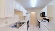 Located at 410 Jason Dr B11 in Richmond, Kentucky, this single-floor unit offers a practical and well-organized layout suited for comfortable everyday living. The galley-style kitchen is outfitted with white cabinetry, light countertops, a double stainless steel sink, and a full suite of appliances including an electric range, dishwasher, microwave, and refrigerator. Light tile flooring runs throughout the kitchen, creating a clean and easy-to-maintain surface. The living area features plush carpeting, a ceiling fan with integrated lighting, and access to natural light through a pair of windows and a glass-paned exterior door, providing a bright and airy feel. The bedroom is generously proportioned with soft carpet, multiple windows that invite natural light, and a notable walk-in closet with built-in shelving, offering ample storage space. The bathroom is finished with tile flooring, a single vanity with a large mirror, and a tub and shower combination with tiled surround. Neutral warm tones are carried consistently throughout the unit, lending the space a cohesive and inviting atmosphere. The overall layout, as seen in the dollhouse view, flows efficiently from the main living area through to the kitchen and private quarters.