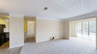 Located at 6300 Moseley Dixon Rd in Macon, GA, this single-floor, three-bedroom, two-bathroom home offers a practical and comfortable layout. The living room is generously sized, featuring plush carpeting, a ceiling fan with light fixture, and multiple windows that fill the space with natural light and offer outdoor views. Each of the three bedrooms continues the warm, neutral color palette with soft carpet flooring and ceiling fans for year-round comfort. The spacious primary bedroom includes a large closet with built-in wire shelving, providing excellent storage capacity, as well as an additional walk-in closet outfitted with multiple shelving tiers. The secondary bedrooms are well-proportioned, with one featuring floor-to-ceiling vertical blinds over a large window. Both bathrooms are equipped with a tub-shower combination and feature wood-look flooring. The full bathroom includes a vanity with a stone-topped countertop, white cabinetry, and a framed mirror. A hallway connects the rooms, creating an efficient and functional flow throughout the home. Clean white trim and neutral walls throughout contribute to a bright, cohesive aesthetic.