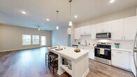 Located at 110 Watersound Lane in Palm Coast, Florida, this thoughtfully designed 2-bedroom, 3-bathroom residence offers a comfortable and modern single-floor layout. The open-concept living and kitchen area serves as the heart of the home, featuring wood-style luxury flooring, neutral warm tones, and a ceiling fan that enhances the airy feel. Natural light filters in through sliding glass doors and windows fitted with blinds.

The kitchen is a standout, boasting crisp white cabinetry, a subway tile backsplash, quartz countertops, a central island with pendant lighting and bar seating, and a full suite of stainless steel appliances including a refrigerator, range, microwave, and dishwasher — ideal for both everyday cooking and entertaining.

Both bedrooms are carpeted for comfort and include ceiling fans and windows that bring in natural light. The spacious primary bedroom offers a generous footprint with two windows overlooking the surrounding neighborhood. Each of the three bathrooms is finished with quartz vanity tops and wood-style flooring; one features a soaking tub with elegant marble-style tile surround, while another offers a bright, window-lit design. A dedicated laundry room with full-size washer and dryer hookups and overhead shelving adds everyday convenience to this well-appointed home.