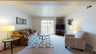 Located at 3550 Breckenridge Ct in Fitchburg, Wisconsin, this single-floor residence offers a well-organized layout designed for comfortable everyday living. The spacious living room is a welcoming centerpiece, featuring soft carpeting, neutral walls, and a large sliding glass door that fills the space with natural light and opens to a private balcony with outdoor views. Adjacent to the living room, a dedicated dining area provides an intimate setting accented by a ceiling fan with integrated lighting. The kitchen is thoughtfully designed with warm wood cabinetry, dark granite-style countertops, tile flooring, and ample storage through both upper and lower cabinets. A range hood over the cooktop and a double sink along the main counter wall complete the functional layout. The bedroom is a calm, carpeted retreat with generous wall space and access to a closet equipped with built-in shelving and hanging rods for organized storage. The bathrooms feature tile flooring, wood-toned vanity cabinetry, white countertops, and large mirrors, offering a clean and practical finish throughout. Consistent warm wood trim and neutral tones unify the interior, creating a cohesive and comfortable atmosphere across the entire home.