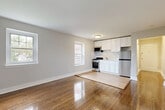 Located along John F. Kennedy Boulevard East in North Bergen, NJ, this efficiently designed single-floor unit makes excellent use of its intimate footprint. The open-plan living, dining, and kitchen area forms the heart of the space, anchored by richly polished hardwood floors that extend throughout. Multiple double-hung windows flood the combined living and dining area with natural light, while a classic radiator provides traditional warmth. The kitchen is neatly integrated into the open layout, featuring white shaker-style cabinetry, a stainless steel refrigerator, a gas range with overhead microwave, and a clean tile backsplash — offering full functionality in a compact design. A hallway connects the main living area to the additional rooms, including two closets that provide practical storage solutions. The bedroom is a serene retreat, benefiting from multiple windows that frame views of the surrounding greenery and include a radiator for climate control. The bathroom is finished in a crisp, all-white palette with subway tile walls, wood-look tile flooring, a white vanity, and a bathtub/shower combination, all illuminated by a frosted window. Two separate entrances add convenience and flexibility to this thoughtfully laid-out North Bergen residence.