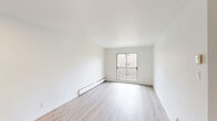 Located at 6965 Rue De Choisy in Montréal, this well-organized one-bedroom, one-bathroom unit offers a clean and functional layout across a single floor. Light wood-style flooring runs consistently throughout the space, contributing to a bright and cohesive aesthetic.

The living room is the largest area of the unit, featuring a sliding glass door that opens to a private balcony with an outdoor view, allowing natural light to fill the room. Neutral white walls and a recessed ceiling light keep the space feeling open and versatile.

The bedroom is a comfortable size, featuring a large built-in sliding-door closet that provides ample storage. A window overlooks greenery outside, and a baseboard heater ensures warmth during colder months.

The kitchen is efficiently designed in an L-shaped layout, with white cabinetry featuring brushed gold hardware, dark stone-effect countertops, a white subway tile backsplash, and a stainless steel sink. The cabinetry extends to the upper walls, maximizing storage capacity.

The bathroom is finished with floor-to-ceiling white square tiles surrounding a full soaking tub with an overhead shower. A curtain rod spans the tub, and the space is completed with warm wood-style flooring that ties in with the rest of the unit.