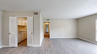 This single-floor residence provides a practical and comfortable layout across a thoughtfully utilized footprint. The living room serves as the central gathering space, featuring light gray wood-look vinyl flooring, neutral beige walls, a textured ceiling, and a large window that invites natural light and outdoor views. The space flows openly toward a hallway leading to the private quarters.

The kitchen is equipped with white cabinetry, speckled laminate countertops, a double stainless steel sink, and a dishwasher, offering efficient functionality. Adjacent to the kitchen is a dedicated laundry area with washer and dryer hookups, overhead shelving, and louvered closet doors for convenient concealment.

Both bedrooms are carpeted and feature neutral walls, natural light from windows with exterior views, and a quiet, restful ambiance. The spacious primary bedroom provides a comfortable retreat. Two closets offer additional storage throughout the unit.

The two bathrooms each include a tub-shower combination with white tile surround, toilet, and vanity with sink, finished with wood-look tile flooring for easy maintenance. Two hallways connect the living areas to the bedrooms and bathrooms, contributing to a well-organized and efficient flow throughout the residence.