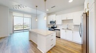 Located at 1605 N Stemmons Freeway in Dallas, TX, this thoughtfully designed one-bedroom, two-bathroom residence offers a clean, contemporary aesthetic throughout its well-utilized single-floor layout. Light hardwood flooring runs through the main living areas and bedroom, lending warmth and continuity to the space.

The kitchen serves as a central highlight, featuring crisp white shaker cabinetry, a large quartz-topped island with built-in storage, stainless steel appliances including a refrigerator, electric range, microwave, and dishwasher, and elegant gold pendant lighting. A subway tile backsplash and recessed lighting complete the polished look.

The bedroom is bright and airy, benefiting from a large window that frames panoramic views of the Dallas skyline and surrounding cityscape. A ceiling fan adds comfort, and roller shades provide privacy. The elevated vantage point makes natural light a defining feature of this room.

The two bathrooms are finished in a neutral, spa-like palette with large-format light tile flooring. The primary bath includes a spacious walk-in shower with a rain showerhead, white cabinetry with brushed hardware, and a well-lit vanity mirror. The layout is clean and functional, maximizing the available space efficiently. Overall, the unit presents a modern, move-in-ready aesthetic with quality finishes throughout.