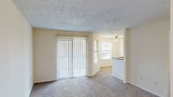 Located at 100 Hunt Club Dr in Copley, Ohio, this one-bedroom, one-bathroom residence offers a well-organized, single-floor layout with a practical and comfortable design throughout. The living area features soft carpeting, a textured ceiling, and a large sliding glass door dressed with vertical blinds that fills the space with natural light. A ceiling fan overhead adds to the room's functionality and comfort. The kitchen flows openly from the dining area and is equipped with stainless steel appliances, including a range, microwave, and refrigerator. White cabinetry pairs cleanly with granite countertops, which extend to a peninsula with a double undermount sink — ideal for casual dining or meal prep. The bedroom is a well-proportioned retreat with plush carpeting, a window overlooking the surrounding neighborhood, and a ceiling fan with light fixture. It connects directly to a spacious walk-in closet outfitted with multiple hanging rods and built-in shelving for ample storage. The bathroom is neatly appointed with a white vanity featuring granite countertops, a large mirror with overhead lighting, and a full soaking tub with shower combination. Wood-look flooring in the bathroom provides a clean, modern contrast. A hallway connects the rooms efficiently, completing this thoughtfully laid-out residence.