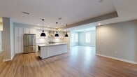 Located at 113 Bridge St in Franklin, Tennessee, this single-floor unit offers a thoughtfully designed open-concept layout finished with contemporary details throughout. Warm hardwood-style flooring flows continuously across the main living areas, unifying the space and enhancing its sense of openness.

The kitchen serves as a central feature, showcasing white shaker cabinetry, granite countertops, and a full suite of stainless steel appliances, including a French door refrigerator, electric range, and a stainless wall-mounted range hood. A subway tile backsplash adds a clean, classic accent, while a central island with pendant lighting provides both additional workspace and a natural gathering point. The kitchen opens directly into the living area, which benefits from a ceiling fan and multiple windows that draw in generous natural light.

Bedroom spaces are finished with the same hardwood-style flooring and feature large windows and glass panel doors that offer views of the surrounding greenery. A spacious walk-in closet with built-in wire shelving provides well-organized storage. Bathrooms are finished with light tile flooring and granite-topped vanities, maintaining a consistent, clean aesthetic. The neutral color palette throughout creates a bright, welcoming ambiance well-suited to a variety of interior styles.