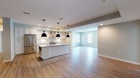 Located at 113 Bridge St in Franklin, Tennessee, this single-floor unit offers a thoughtfully designed open-concept layout finished with contemporary details throughout. Warm hardwood-style flooring flows continuously across the main living areas, unifying the space and enhancing its sense of openness.

The kitchen serves as a central feature, showcasing white shaker cabinetry, granite countertops, and a full suite of stainless steel appliances, including a French door refrigerator, electric range, and a stainless wall-mounted range hood. A subway tile backsplash adds a clean, classic accent, while a central island with pendant lighting provides both additional workspace and a natural gathering point. The kitchen opens directly into the living area, which benefits from a ceiling fan and multiple windows that draw in generous natural light.

Bedroom spaces are finished with the same hardwood-style flooring and feature large windows and glass panel doors that offer views of the surrounding greenery. A spacious walk-in closet with built-in wire shelving provides well-organized storage. Bathrooms are finished with light tile flooring and granite-topped vanities, maintaining a consistent, clean aesthetic. The neutral color palette throughout creates a bright, welcoming ambiance well-suited to a variety of interior styles.