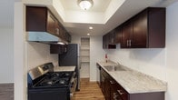 Located at 6977 Bluewater Trl in Marlborough, MO, this single-floor residence offers a thoughtfully designed layout with a clean, modern aesthetic throughout. The galley-style kitchen is a standout feature, showcasing rich dark cabinetry with brushed nickel hardware, granite-look countertops, and stainless steel appliances including a gas range with overhead ventilation hood and a full-size refrigerator. A built-in pantry provides convenient additional storage, and warm hardwood-style flooring ties the kitchen together seamlessly. The open living and dining areas continue the hardwood-style flooring, creating a bright and cohesive space. Large sliding glass doors fitted with vertical blinds allow generous natural light to fill the main living area while offering access to an outdoor view. The bedroom features plush carpeting and a sizable window, also dressed with vertical blinds, that brings in additional natural light. The bathroom includes a full tub-shower combination with chrome fixtures and is finished with tile flooring and a granite-topped vanity. Throughout the space, neutral wall tones and clean finishes create a welcoming, move-in-ready environment suited for comfortable everyday living.