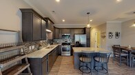 Located at 2220 Boiling Springs Rd in Boiling Springs, South Carolina, this two-story home showcases thoughtfully designed interiors with quality finishes across both levels. The kitchen serves as a central highlight, featuring dark espresso cabinetry, light granite countertops, a mosaic tile backsplash, and stainless steel appliances including a gas range, built-in microwave, and French door refrigerator. A large peninsula with seating provides an ideal casual dining space, while pendant lighting and recessed fixtures illuminate the area effectively. Hardwood-style flooring flows throughout the main living and dining areas, complementing the neutral wall tones and crown molding details.

The dining area offers a clean, open feel with generous wall space and ceiling fan lighting. Bedrooms are generously proportioned, each featuring plush carpeting, tray ceilings with ceiling fans, recessed lighting, and windows that bring in natural light. The primary bathroom includes a dual-sink vanity with granite counters, dark cabinetry, large-format tile flooring, a soaking tub, and a tiled shower surround with decorative mosaic accent banding. A secondary bathroom mirrors the same refined aesthetic with granite counters and tile flooring. Throughout the home, consistent design choices—crown molding, neutral tones, and quality materials—create a cohesive and polished atmosphere.