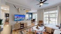 Located at 10809 Westwood Loop in San Antonio, TX, this single-floor, 3-bedroom, 2-bathroom residence offers a thoughtfully designed layout with modern finishes throughout. The galley-style kitchen features white shaker cabinetry with dark hardware, dark countertops, stainless steel appliances, and light hardwood-style flooring—a clean and functional space for cooking and entertaining. The adjacent dining area is bright and inviting, with large windows dressed in sheer white curtains that allow ample natural light and offer views of mature trees outside. A bold blue accent wall adds a striking focal point to the dining space. Each of the three bedrooms showcases distinct character, with hardwood-style floors, natural light from well-placed windows, and accent walls in deep navy and teal tones. The primary bedroom offers a comfortable, cozy scale with warm finishes. The two bathrooms are finished with white cabinetry, dark countertops, and tub-shower combinations—one featuring a bold black-framed vanity mirror. A private balcony extends the living space outdoors, overlooking lush, mature oak trees that provide a serene natural backdrop—a standout feature of this San Antonio residence.