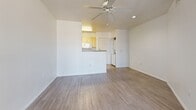 Located at 1333 N 24th St in Phoenix, Arizona, this efficiently designed unit offers a thoughtful single-floor layout that maximizes every square foot. The open-concept living and kitchen area forms the heart of the space, where a peninsula-style breakfast bar with a gray laminate countertop neatly separates the two zones. The kitchen is well-appointed with light wood cabinetry providing ample storage, gray laminate countertops lining both walls, a stainless steel sink, and a full suite of white appliances including an electric range, over-the-range microwave, and refrigerator. The living area is bright and airy, featuring crisp white walls, light wood-style vinyl flooring, a ceiling fan, and a large sliding glass door that fills the room with natural light and provides outdoor access. In-unit laundry connections are also visible, adding everyday convenience. The full bathroom is clean and functional, outfitted with a shower-tub combination, a wood-framed vanity mirror, light countertop, and matching wood cabinetry below. Light wood-style flooring continues throughout, creating a cohesive, modern feel across the entire unit. The overall aesthetic is clean, neutral, and move-in ready.