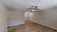 This single-floor unit offers a practical and comfortable layout designed with functional living in mind. The living area features warm-toned wood-look flooring that extends throughout the space, clean neutral wall tones, crisp white baseboards, and a textured ceiling fitted with a ceiling fan and light fixture — a consistent design element found across multiple rooms. A window with blinds allows natural light to fill the living area, which also includes a dedicated entry door.

The kitchen is well-equipped with white shaker-style cabinetry, a classic subway tile backsplash, and a full suite of stainless steel appliances including a refrigerator, electric range, and over-the-range microwave. Track lighting illuminates the workspace, and a stacked washer and dryer unit is conveniently integrated into the kitchen area, offering in-unit laundry.

The bedroom is generously sized, bathed in natural light through a window with blinds, and features a ceiling fan overhead. A spacious walk-in closet provides ample storage, while an additional doorway connects to the rest of the unit for easy flow.

The bathroom includes a full tub and shower combination with a clean white surround, chrome fixtures, and a showerhead, maintaining the unit's consistent, no-fuss aesthetic throughout.