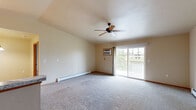 Located at 1951 Scheuring Rd in De Pere, Wisconsin, this 2-bedroom, 2-bathroom unit offers a practical and comfortable single-floor layout. The living room is a standout feature, boasting vaulted ceilings, plush carpeting, a ceiling fan, and a wall-mounted air conditioning unit. A sliding glass door opens to a private balcony, filling the space with natural light and outdoor views of the surrounding neighborhood. Baseboard heating runs throughout the unit, ensuring year-round comfort.

The kitchen is well-appointed with warm honey-toned oak cabinetry, light granite-style laminate countertops, a double stainless steel sink, and a full suite of white appliances including a range, microwave, refrigerator, and dishwasher. Track lighting overhead and tile flooring complete the functional cooking space.

Both bedrooms are carpeted and feature neutral walls, wood-trimmed windows that allow in natural light, and sliding wood closet doors providing generous storage. The two bathrooms are finished with tile flooring, oak vanities with white countertops, and tub/shower combinations. Connecting hallways provide an efficient flow throughout the unit, making this a well-organized and comfortable home.