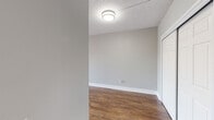 This single-floor residence offers a clean, functional layout designed for comfortable everyday living. Throughout the space, warm medium-toned hardwood-style flooring creates a cohesive and inviting aesthetic, complemented by neutral gray walls and crisp white baseboards and trim.

The living areas are generously sized and bathed in natural light, courtesy of large windows fitted with horizontal blinds. Ceiling fans are present in the main living spaces, providing both airflow and ambient lighting. Textured popcorn ceilings add a classic finishing touch throughout.

The kitchen is a standout feature, showcasing white shaker-style cabinetry with brushed nickel hardware, speckled granite countertops, a stainless steel undermount sink with a curved gooseneck faucet, and a stainless steel dishwasher. The layout provides ample counter space and storage for everyday cooking needs.

The bedroom offers comfortable proportions, a large window for natural light, a ceiling fan, and a double sliding-door closet for generous storage. An additional door provides convenient access to a secondary closet or adjacent space.

The bathroom is neatly appointed with white subway tile surrounding a tub-shower combination with a handheld showerhead, a dark accent tile border, a built-in niche, a granite-topped vanity, and wood-style flooring. The overall design is clean, practical, and move-in ready.