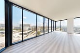 This contemporary high-rise unit offers a bright, open layout defined by clean lines and a neutral palette throughout. Light wood flooring flows seamlessly across every room, complementing the crisp white walls and creating a cohesive, airy ambiance.

The open-concept living area is anchored by dramatic floor-to-ceiling glass windows and doors framed in dark navy, wrapping around the space to deliver panoramic city skyline views and an abundance of natural light. A private balcony extends the living space outdoors, offering elevated vistas of the surrounding urban landscape.

The modern kitchen is a standout feature, equipped with a large central island topped with white quartz countertops, dark cabinetry, white upper cabinets, a textured tile backsplash, a stainless steel range hood, and globe pendant lighting. The layout connects effortlessly to the living and dining areas, making it ideal for entertaining.

The bedrooms are generously proportioned, each benefiting from large windows and plentiful natural light. One bedroom is accompanied by a spacious walk-in closet outfitted with wire shelving systems for ample storage.

The en-suite bathroom is finished in a contemporary style, featuring dual under-mount sinks set into a white quartz vanity, sleek dark cabinetry, a large illuminated mirror, a glass-enclosed shower, and light tile flooring. A bright entry hallway with recessed lighting completes this well-appointed space.