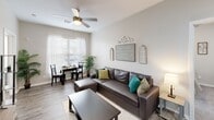 Located at 1300 Independence Place Dr in Hinesville, GA, this single-floor, 2-bedroom, 2-bathroom residence offers a thoughtfully designed layout with modern finishes throughout. Wood-look luxury vinyl flooring flows through the main living areas, while neutral tones create a clean, cohesive aesthetic from room to room.

The open living room is bright and welcoming, featuring a ceiling fan, large windows that invite natural light, and space for both a seating and dining area. It connects seamlessly to the kitchen, which is equipped with stainless steel appliances including a range and over-the-range microwave, white shaker cabinetry, and granite-style countertops. A pantry provides additional storage convenience.

The primary bedroom is a comfortable retreat with plush carpeting, a ceiling fan, and ample closet space. The second bedroom features a window with natural light and built-in shelving. Both bathrooms are fitted with wood-look flooring, grab bars for accessibility, a vanity with granite-style counters, and a tub-shower combination.

A dedicated laundry room houses a full-size washer and dryer, adding everyday practicality. With three closets providing generous storage throughout, this well-appointed residence delivers a functional and comfortable living experience.
