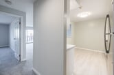 This single-floor residence offers a clean, contemporary design throughout, with neutral tones, fresh finishes, and an efficient layout. The kitchen is well-equipped with white shaker-style cabinetry, light quartz countertops, a stainless steel refrigerator, dishwasher, and light wood-look flooring that enhances its bright, modern feel. Recessed lighting and a pass-through window connect the kitchen to the main living area, which features soft carpeting, recessed lighting, and a generous open feel ideal for everyday living. A spacious second living or bedroom area is highlighted by sliding glass doors leading to a private balcony, offering sweeping elevated views of the surrounding cityscape. An additional bedroom captures remarkable water views through its window, filling the room with natural light and scenic vistas. The bathroom is finished in crisp white, featuring large-format tile flooring, a white vanity with a medicine cabinet mirror, and a tiled shower-tub combination with a decorative mosaic accent strip. A carpeted hallway connects the rooms, providing smooth flow throughout the unit. The overall ambiance is bright, airy, and move-in ready, with consistent modern finishes across every space.