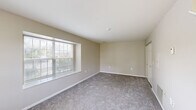 This two-story home in Canton, MI offers a practical and comfortable layout spread across two floors. The main level features a galley-style kitchen equipped with warm honey-toned wood cabinetry, granite countertops, a subway tile backsplash, stainless steel appliances including a refrigerator, range, microwave, and dishwasher, and light wood-style flooring. Adjacent to the kitchen is a dining and living area illuminated by natural light from a large window and complemented by a ceiling fan. A dedicated in-unit laundry closet adds everyday convenience on this level. The bathrooms are finished with granite-topped white vanities, brushed gold hardware, and clean, modern fixtures — one featuring a tub-shower combination with wood-style flooring, and another with a granite vanity and well-lit mirror. Both bedrooms are located on the upper floor, each featuring plush carpet, generous closet space, and ample natural light. The spacious primary bedroom benefits from dual windows on a corner wall, creating a bright and airy retreat. Neutral warm-beige tones throughout the home contribute to a cohesive and inviting ambiance, making this Canton residence a well-equipped and move-in-ready home.