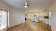Located in Panama City Beach, Florida, this well-appointed 2-bedroom, 2-bathroom residence offers a thoughtfully designed single-floor layout with contemporary finishes throughout. The open-concept kitchen serves as the heart of the home, featuring white shaker-style cabinetry extending to the ceiling, granite countertops, a subway tile backsplash, and a full suite of stainless steel appliances including a French door refrigerator, electric range, and built-in microwave. A central island with a granite surface and undermount sink provides additional prep space and casual seating, while pendant lighting adds a polished touch overhead. Wood-look flooring flows seamlessly through the main living and kitchen areas, complemented by ceiling fans throughout. The open living area is bright and airy, with natural light filtering in through window-blinded windows. Both bedrooms are generously proportioned, featuring plush carpet flooring, ceiling fans, and natural light from exterior windows. The two full bathrooms are finished with granite-topped vanities, wood-look flooring, and tiled tub-shower combinations with neutral subway tile surrounds. The overall ambiance is clean, modern, and move-in ready, reflecting a cohesive design aesthetic ideal for comfortable Florida living.