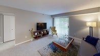 This single-floor residence offers a thoughtfully designed layout that balances comfort and functionality across its key living spaces. The living room serves as the heart of the home, featuring plush carpeting, neutral gray walls, and a large sliding glass door dressed with vertical blinds that floods the space with natural light and provides views of the surrounding greenery outside.

The kitchen is equipped with warm wood cabinetry, granite-style countertops, a stainless steel sink, and a dishwasher. Durable hardwood-style flooring runs through the kitchen and extends into a dedicated laundry room, which also houses the electrical panel — a practical and space-efficient arrangement.

The primary bedroom is a serene retreat with carpet flooring, soft neutral tones, natural light from a window with blinds, and direct access to a private en-suite bathroom. The en-suite features a granite-top vanity with wood cabinetry, hardwood-style flooring, and a shower-tub combination. A second bedroom offers a comfortable and versatile space, also carpeted, with its own window and walk-in closet. A second full bathroom mirrors the granite vanity finishes found throughout, maintaining a cohesive aesthetic. The consistent use of neutral tones, granite surfaces, and wood-toned cabinetry gives the entire residence a unified and well-maintained character.